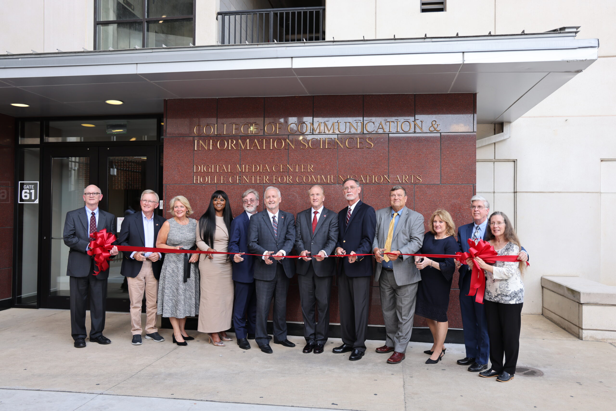 Group of individuals stand outside for a building ribbon cutting